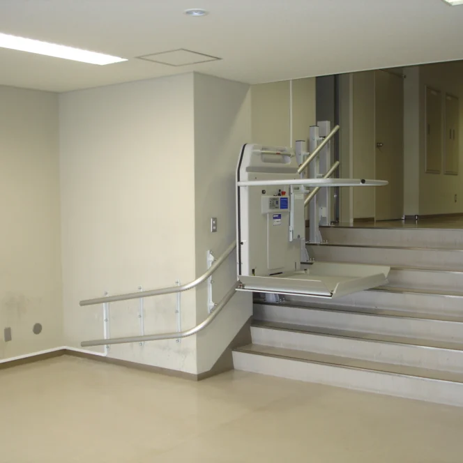 A wheelchair lift installed beside a short flight of stairs in a building, providing accessibility for people with mobility impairments.