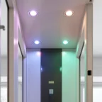 A hallway ceiling with four recessed lights, each emitting a different color: purple, yellow, blue, and green, creating a modern and colorful atmosphere.
