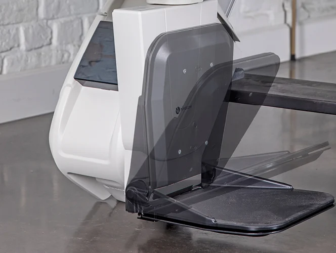 A close-up of a rowing machine’s footrest in two positions, showing its adjustable mechanism on a polished concrete floor.
