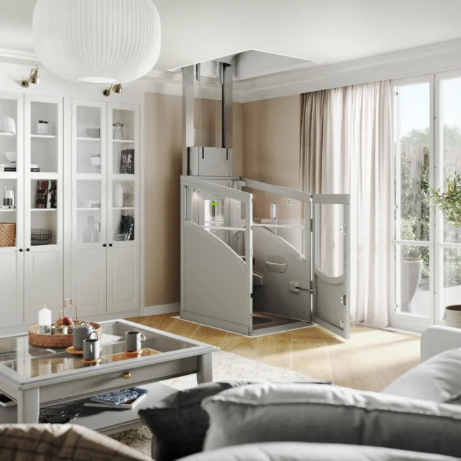 In een moderne woonkamer met lichte meubels en grote ramen is een compacte huislift met glazen deuren geïnstalleerd.
