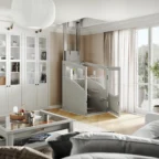 L'intérieur d'une maison moderne comprend un ascenseur résidentiel compact situé à côté de grandes baies vitrées et de vitrines, avec une table basse et un canapé au premier plan.