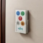 Un panneau de commande d'ascenseur mural doté de six boutons colorés, comportant des flèches, un symbole représentant une main et des icônes d'avertissement, portant la mention « Pollock Lifts ».
