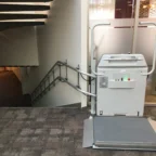 A wheelchair lift is installed next to a staircase in an indoor setting, providing accessibility between floor levels.