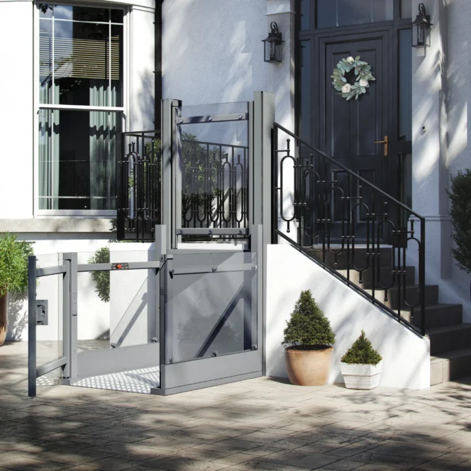 A residential wheelchair lift is installed next to outdoor steps leading to a front door, providing accessible entry to the home.