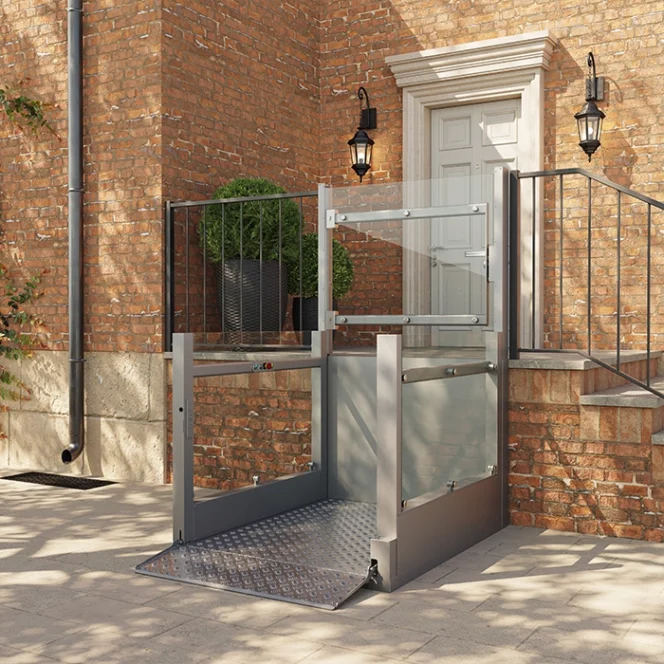 A metal wheelchair lift installed outside a brick building provides accessible entry to a raised doorway with stairs and black railings.