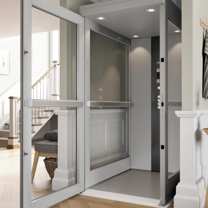 Ein moderner Hausaufzug mit Glastüren und Innenbeleuchtung, der sich neben einer Treppe in einem modernen Wohnhaus befindet.