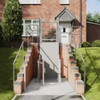 A residential wheelchair lift installed between brick steps provides accessible entry to a doorway at the front of a house.