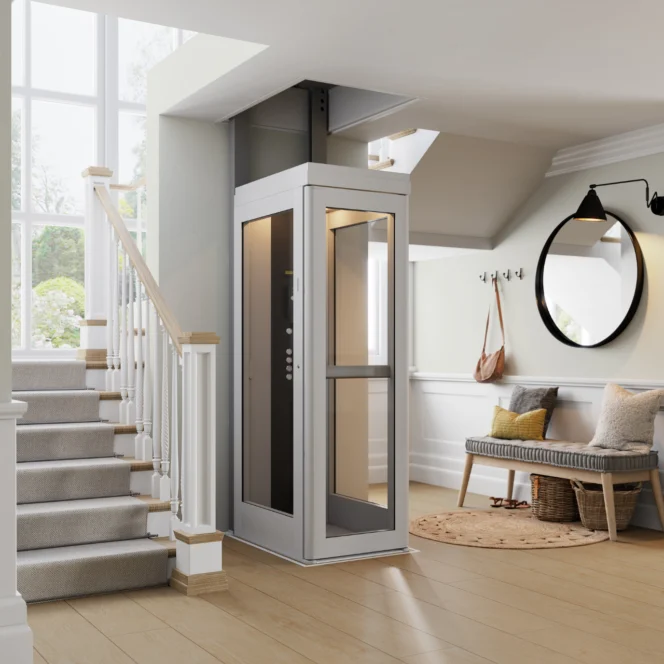 Naast de trap in een lichte hal met lichte muren, een houten vloer, een bankje, kapstokken en een ronde spiegel is een moderne huislift geïnstalleerd.