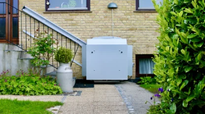 A white wheelchair lift is installed next to stairs outside a brick house, providing accessible entry from a garden pathway.