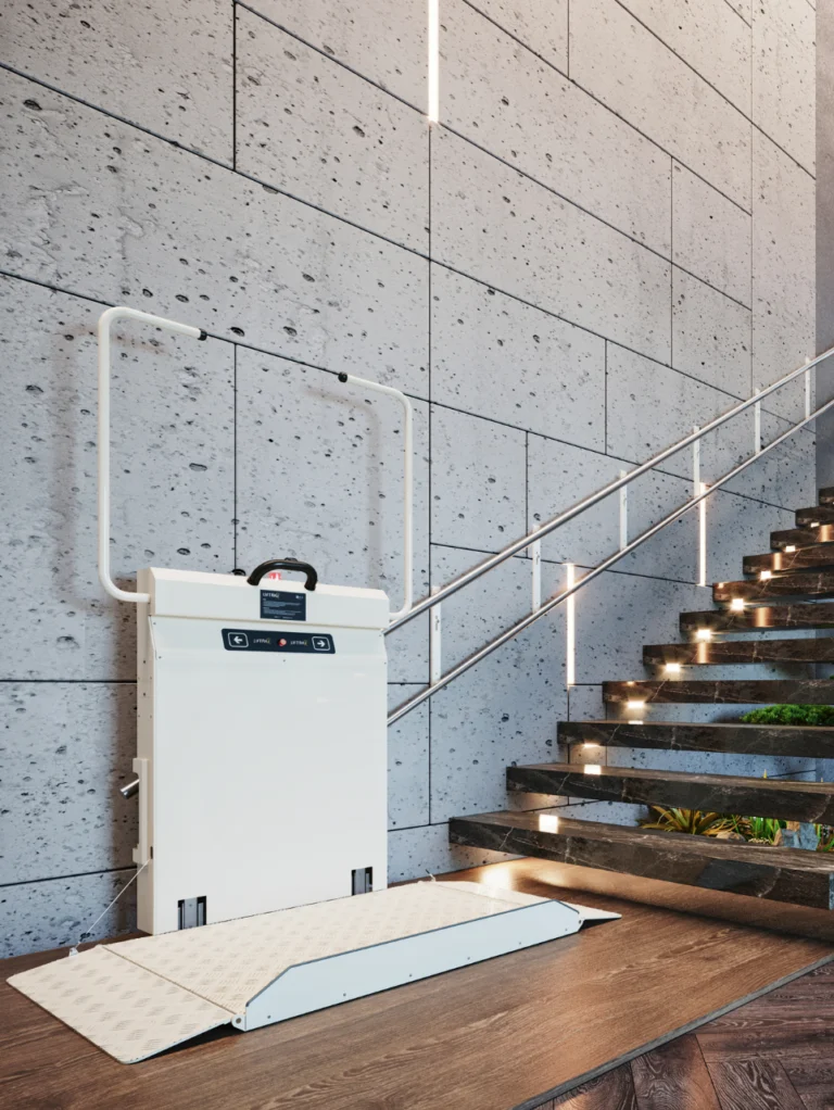 A stairlift platform is installed next to a staircase with glass railings in a modern building with a stone wall.
